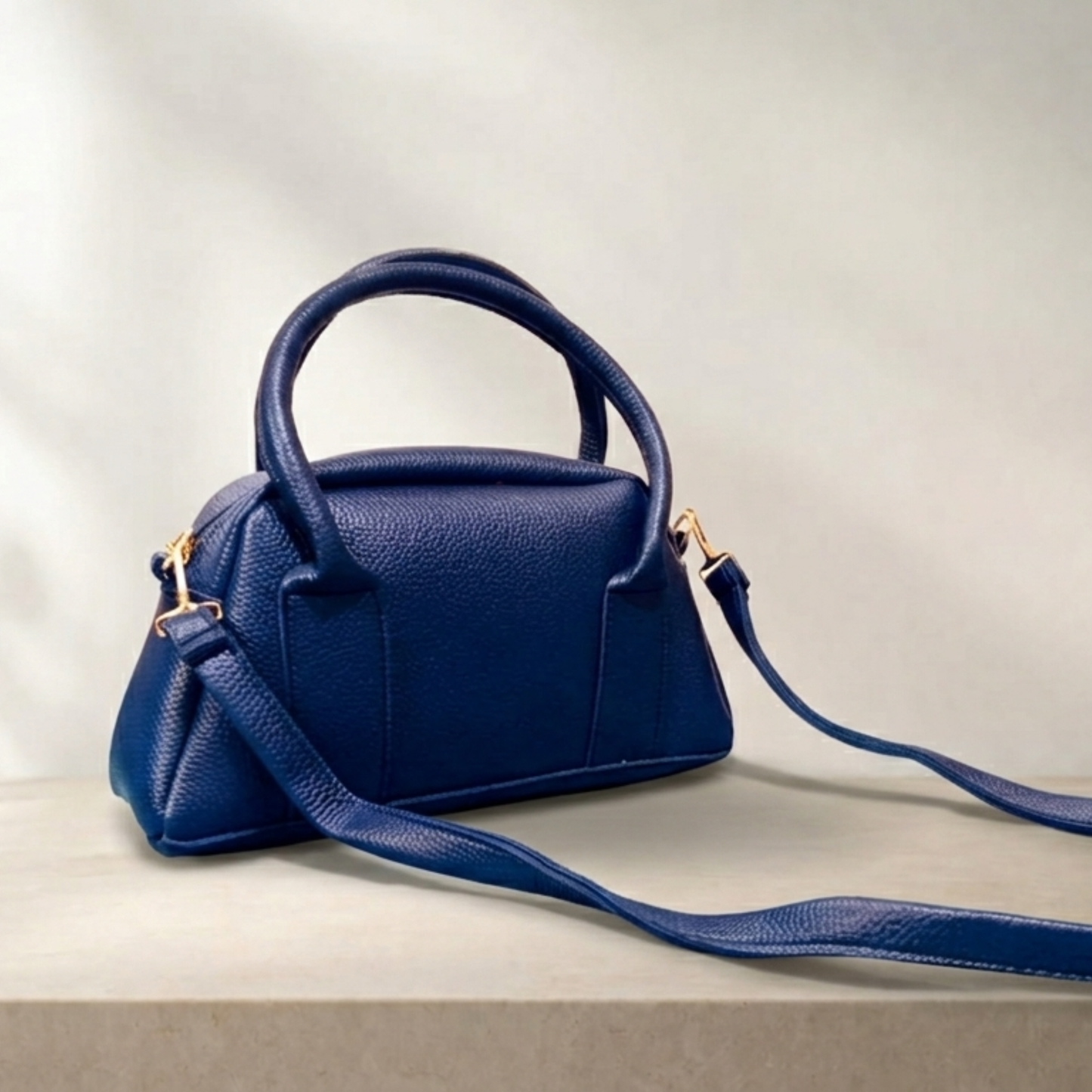 Blue handbag with a matching strap on a light background