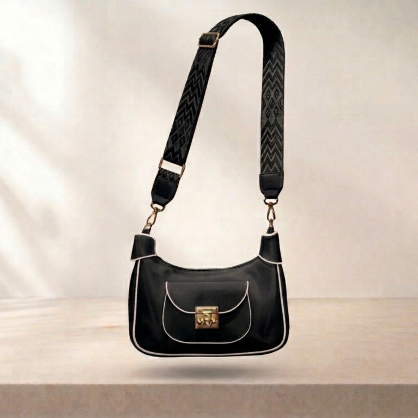 Black handbag with a strap on a light background