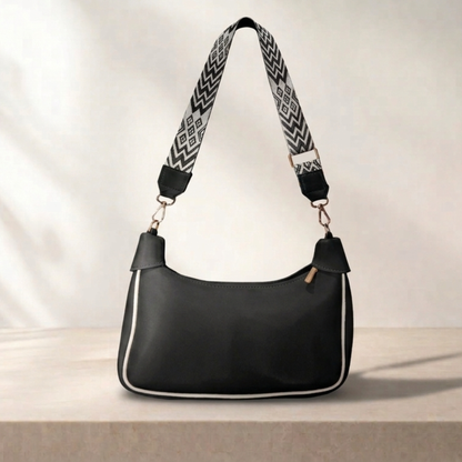Black handbag with a patterned strap on a light background