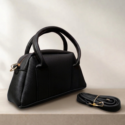 Black handbag with matching strap on a light background