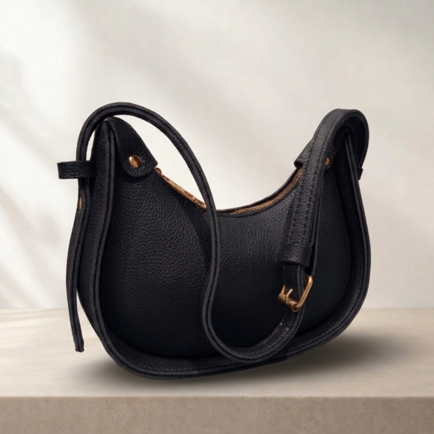 Black leather handbag with gold accents on a neutral background
