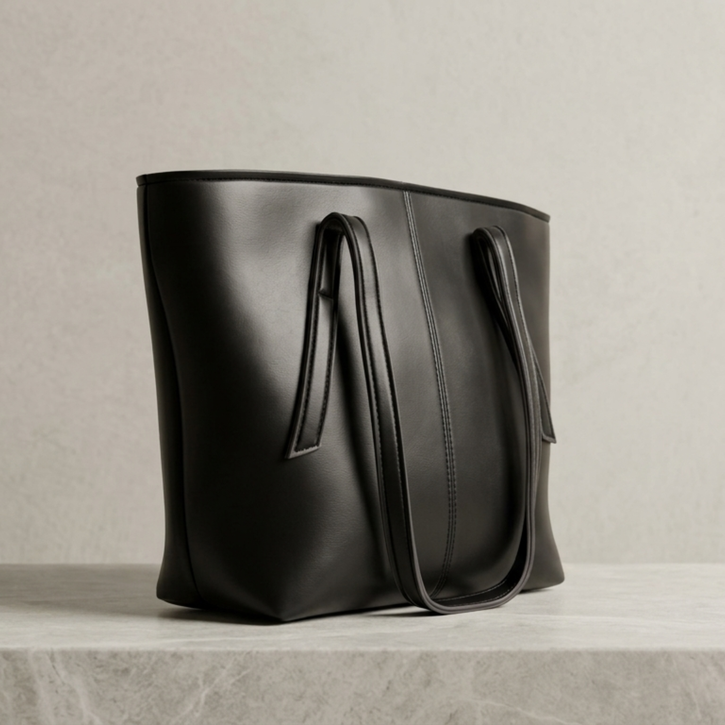 Black leather tote bag on a light gray background