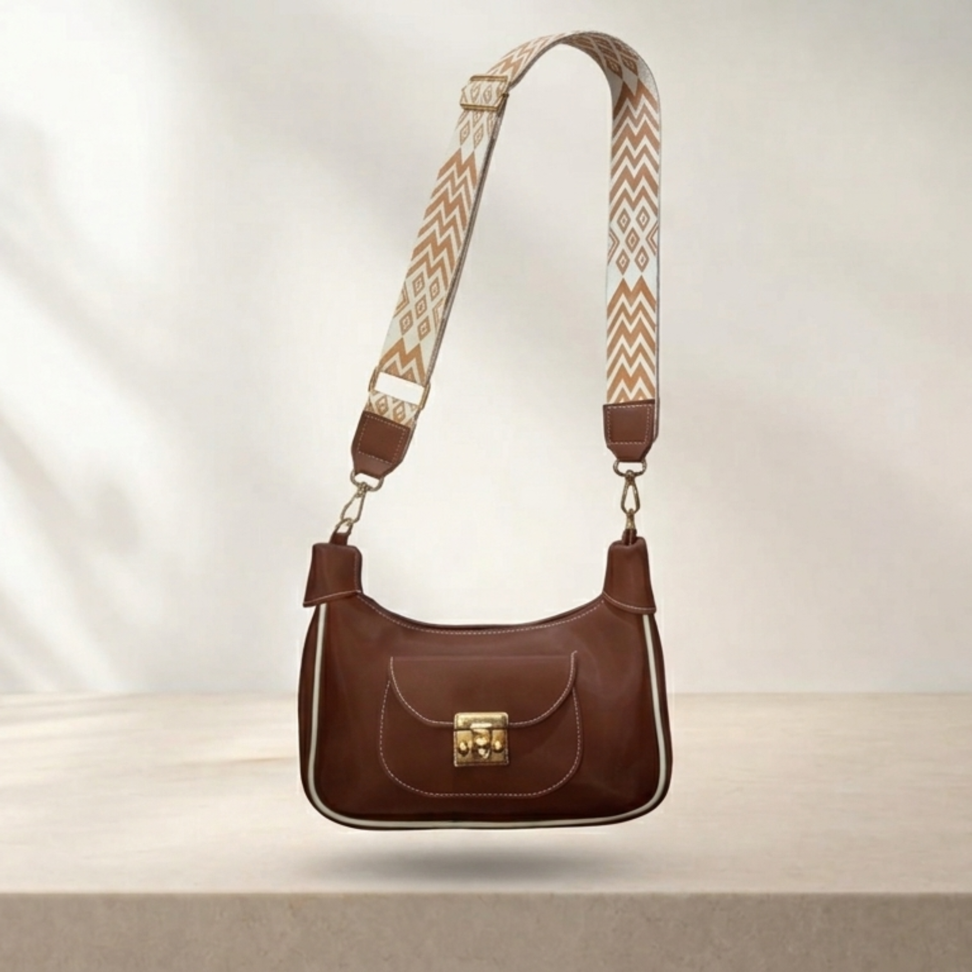 Brown handbag with a patterned strap on a light background