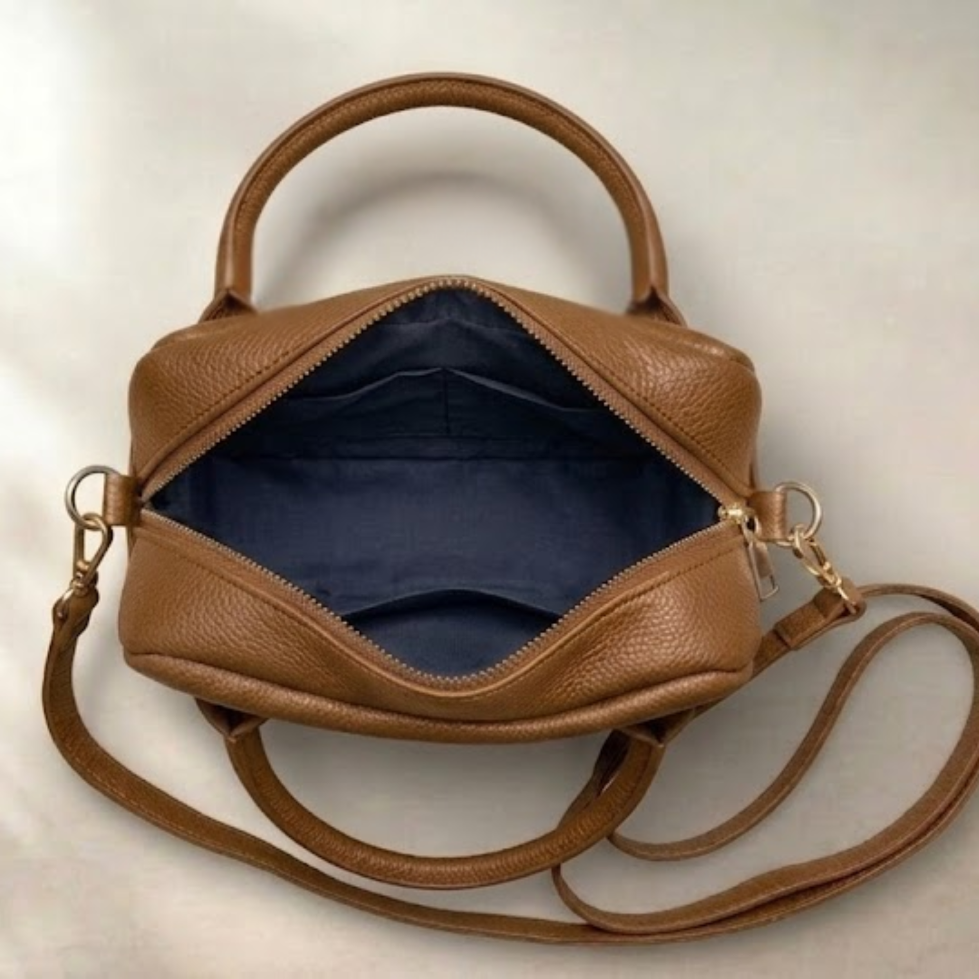 Brown leather handbag with a shoulder strap on a light background
