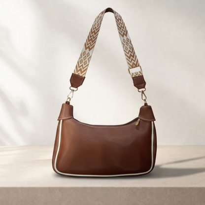 Brown handbag with a patterned strap on a light background