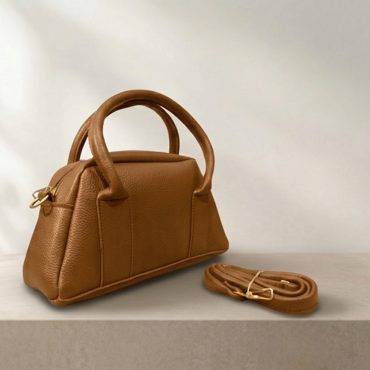 Brown leather handbag with matching strap on a light background