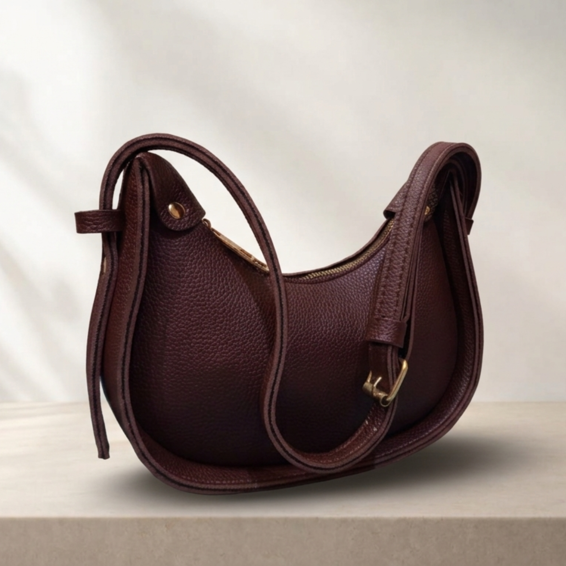 Brown leather handbag with gold accents on a light background