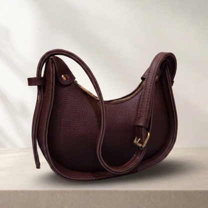 Brown leather handbag with gold accents on a light background