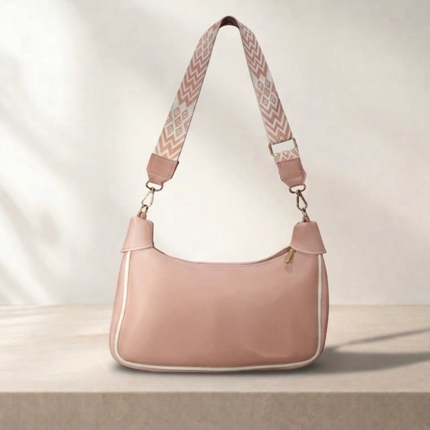 Pink handbag with a patterned strap on a light background