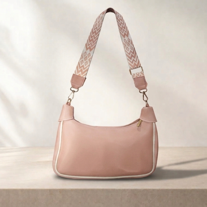Pink handbag with a patterned strap on a light background