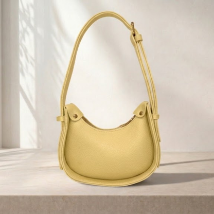 Yellow handbag on a light beige surface with a neutral background