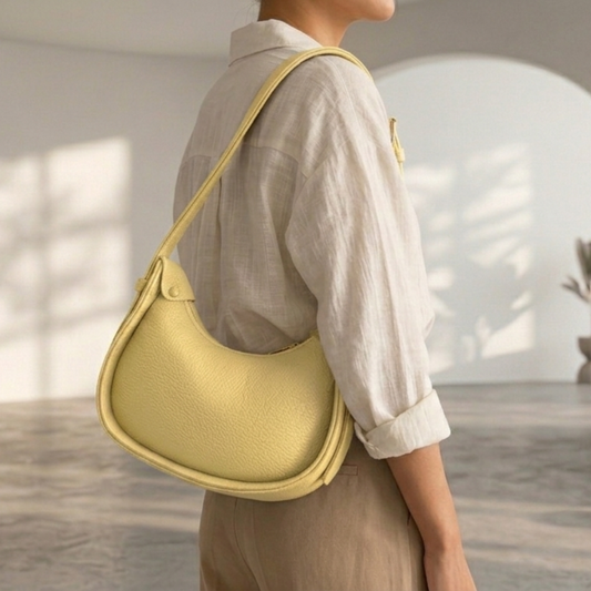 Person wearing a light-colored shirt and holding a yellow shoulder bag indoors.