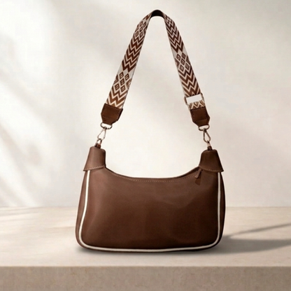Brown handbag with a patterned strap on a light background