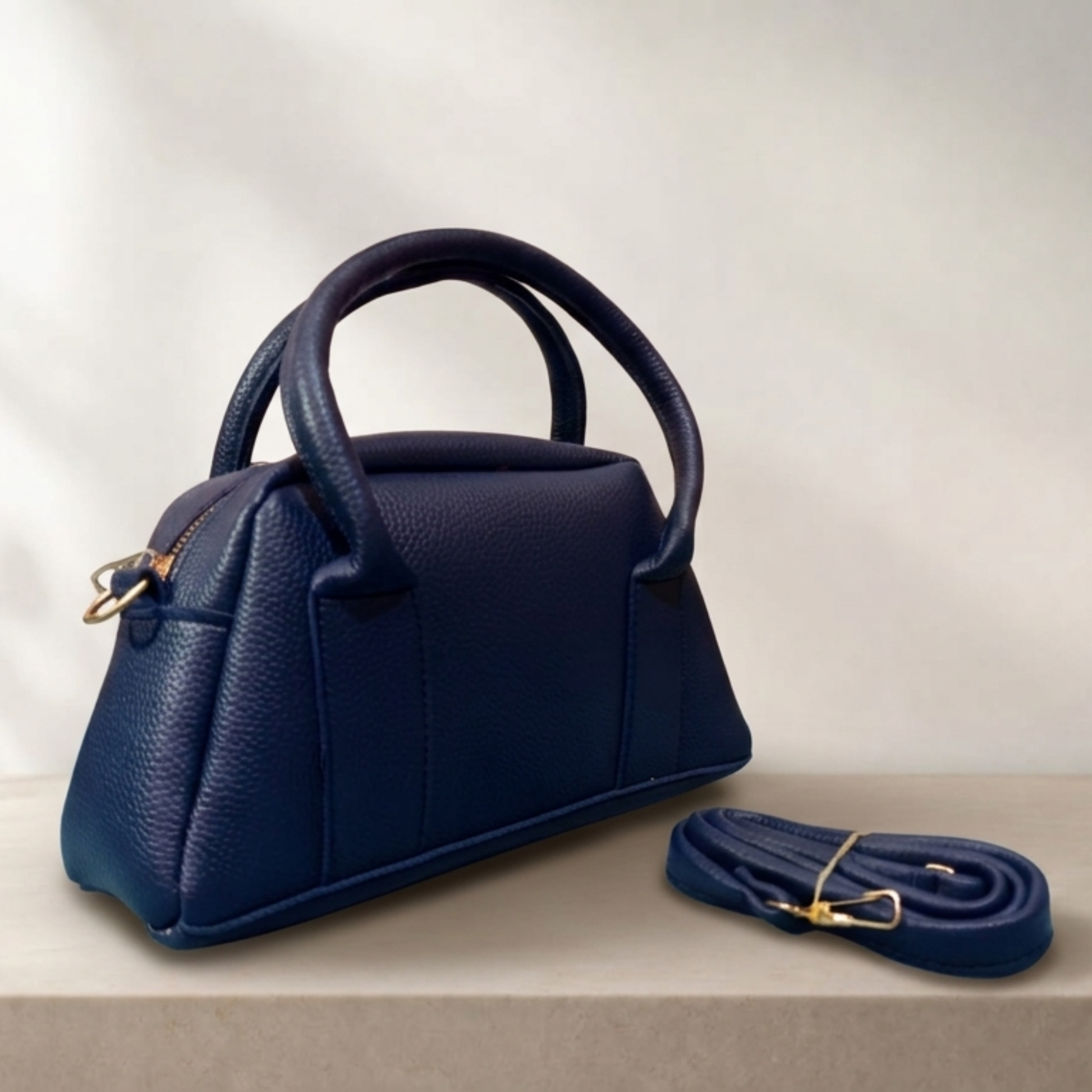 Black handbag with matching strap on a light background