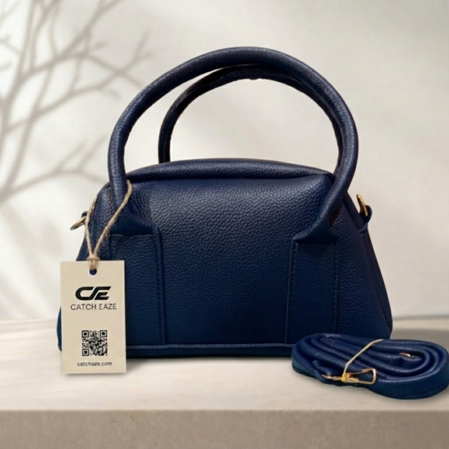 Navy blue handbag with a matching strap on a light background, featuring a 'Catch Eaze' tag.