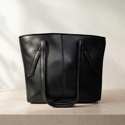 Black leather tote bag on a light beige background