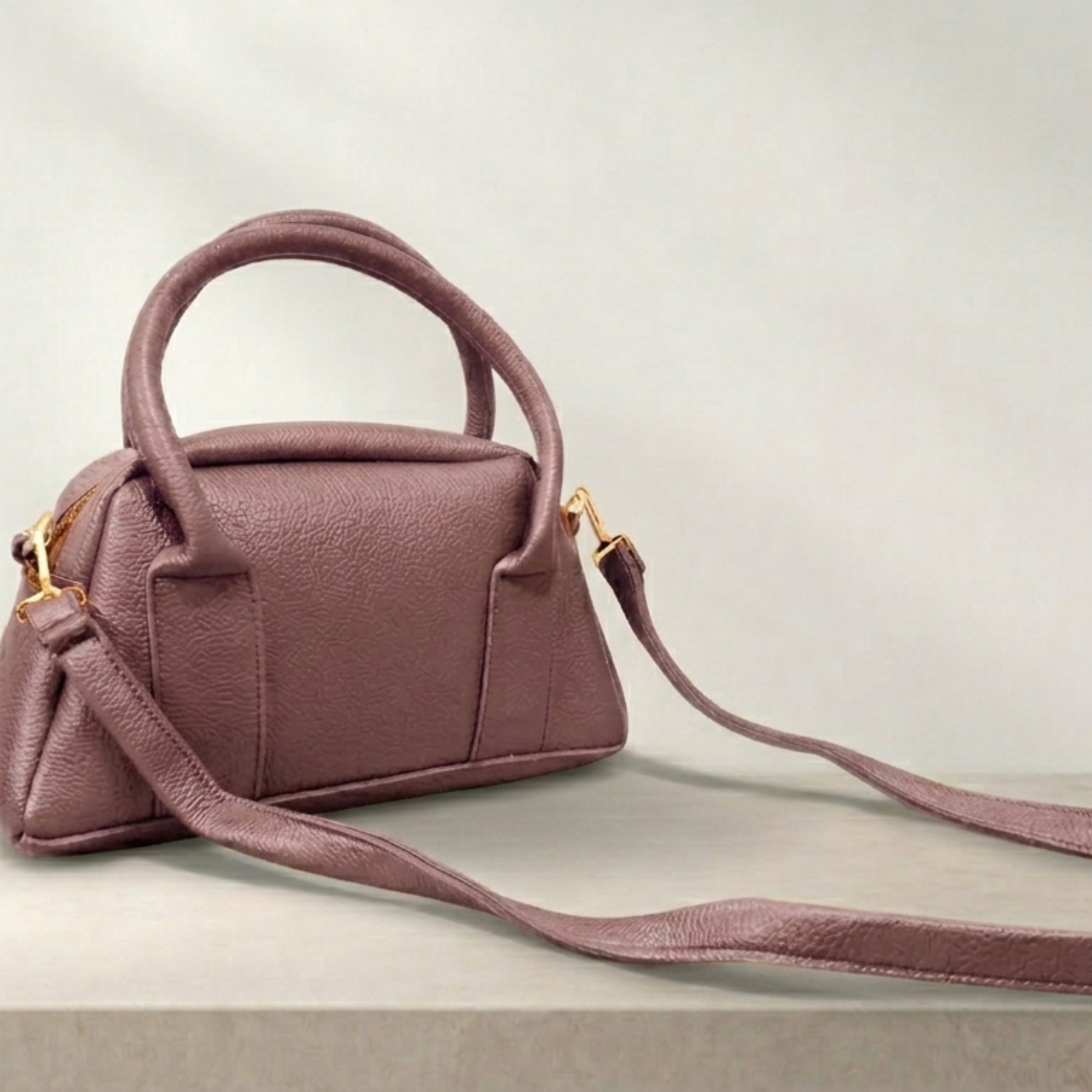 Pink handbag with a strap on a light gray background