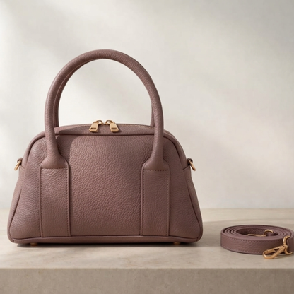 Pink handbag with matching strap on a light background